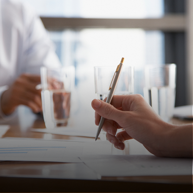 Hand holding pen during business meeting.
